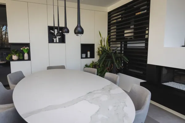 Ronde eettafel voor een witte kastenwand en zwarte lamellen, realisatie van ID Interieur