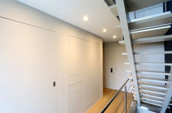 Witte inbouwkasten naast een open trap, realisatie van ID Interieur