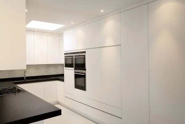 Witte keuken met zwart werkblad en inbouwovens, realisatie van ID Interieur